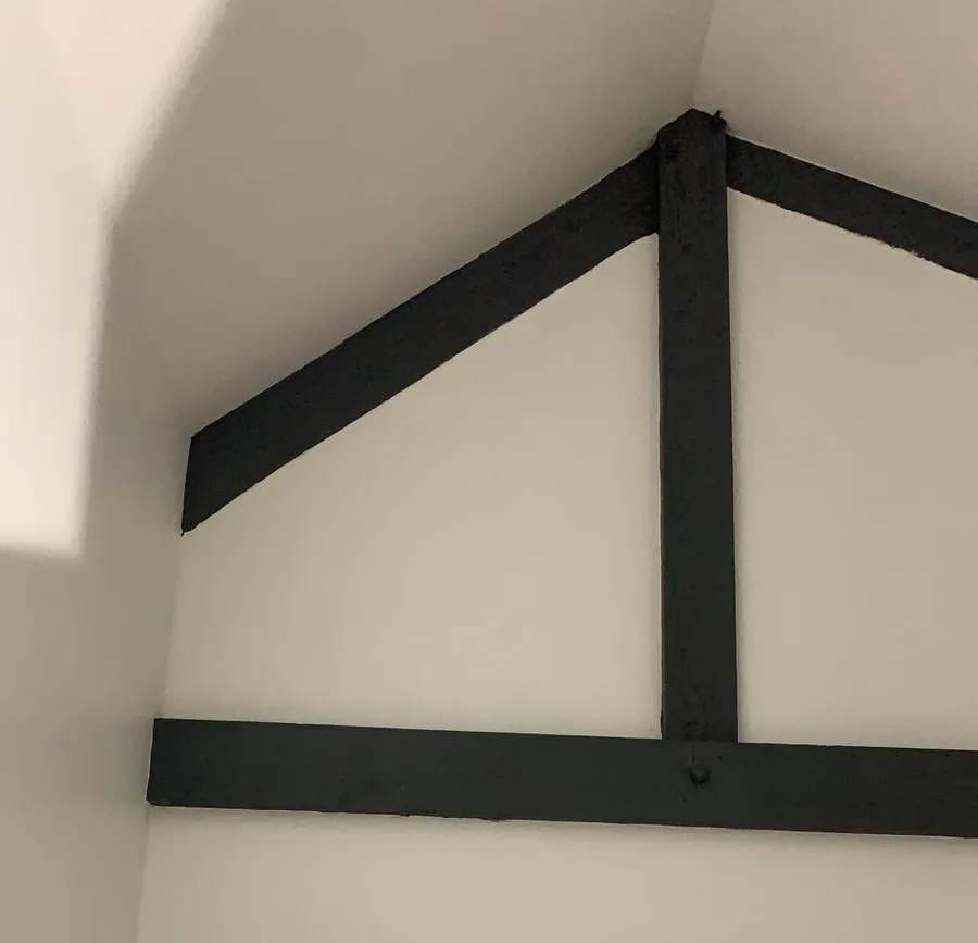 Charpente de combles peinte en gris anthracite sur murs blancs